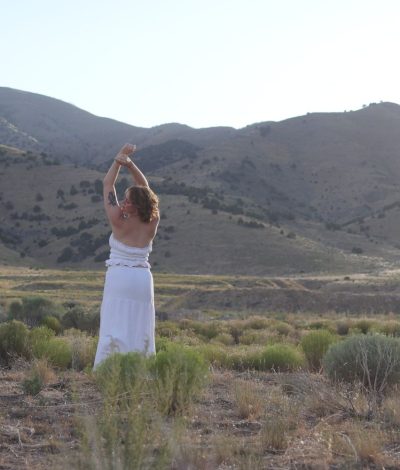 girl posing with hands above her head in field