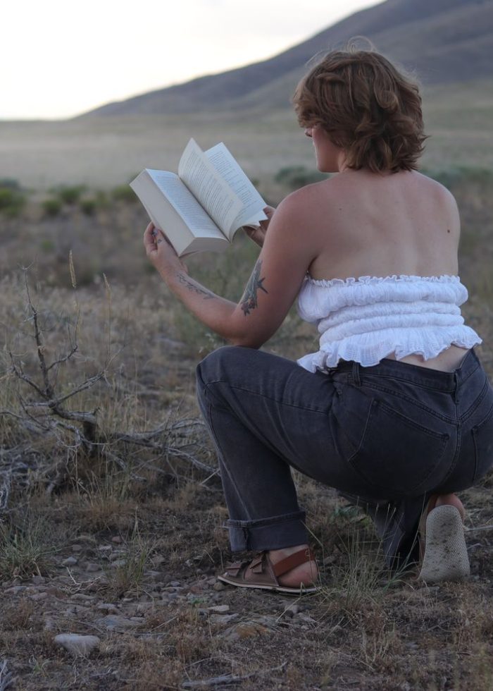 girl sitting on grass holding book open.