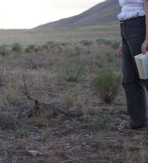 girl walking in field holding a book in her hand