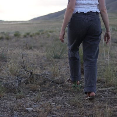 girl with black jeans walking in a grass field