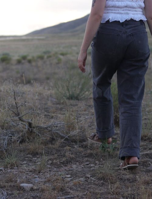 girl with black jeans walking in a grass field